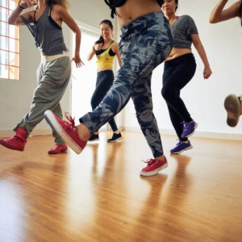 Sporty women enjoying each others company while doing leg swings during fitness training