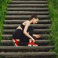 Pretty lady training in a summer city. Brunette doing yoga. Gitl in a sportsuit.
